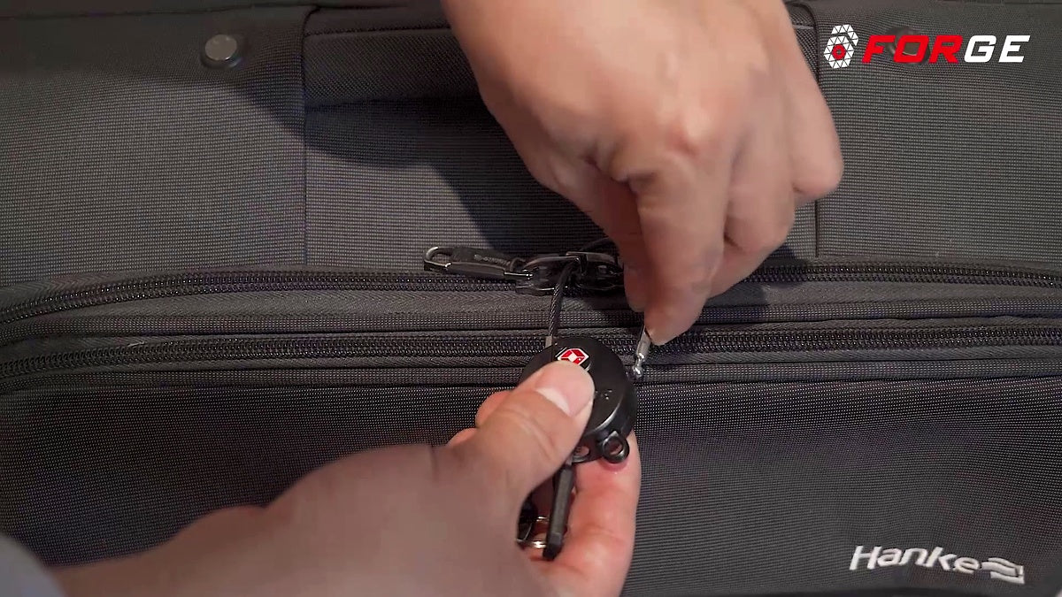 A person unlocking a TSA lock on a suitcase zipper.