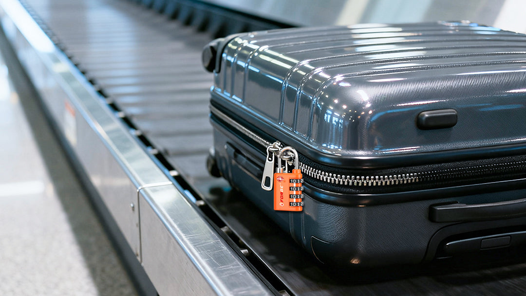 A black suitcase secured with an orange TSA lock on an airport baggage conveyor belt.
